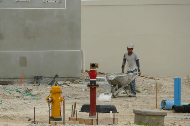 Construction worker pushes a wheelbarrow at Marco Island Executive Airport on July 20, 2020.