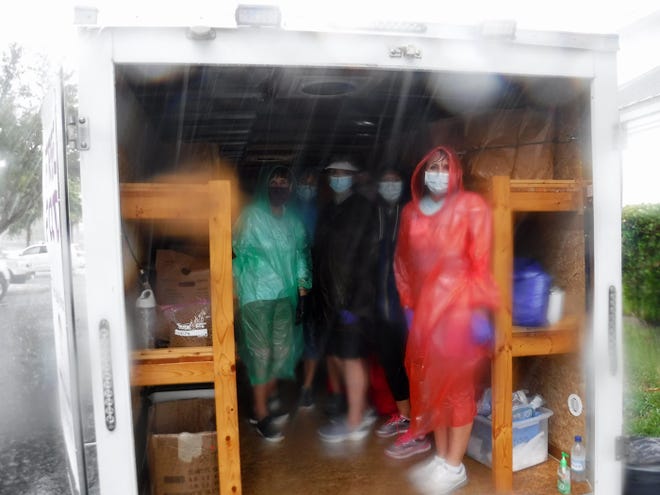 Volunteers huddle in their trailer as the rain pours down. Our Daily Bread Food Pantry delivered much needed groceries to hungry recipients Friday afternoon at St. Mark's Episcopal Church from its moblie food pantry, despite a torrential downpour.