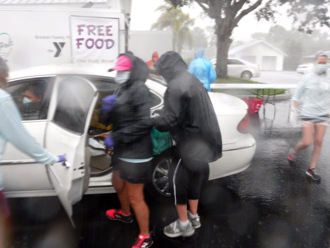 Volunteers load up vehicles in the driving rain. Our Daily Bread Food Pantry delivered much needed groceries to hungry recipients Friday afternoon at St. Mark's Episcopal Church from its moblie food pantry, despite a torrential downpour.