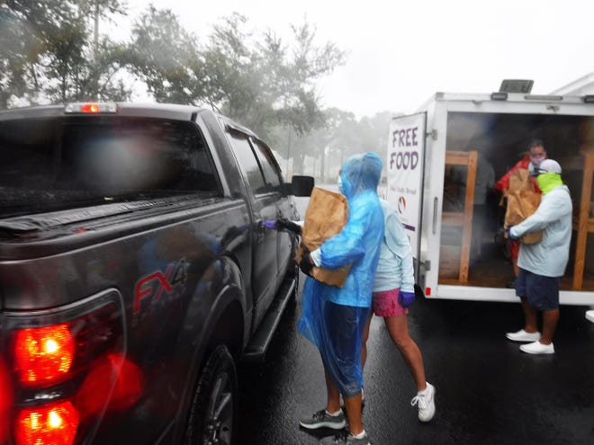 Volunteers load up vehicles in the driving rain. Our Daily Bread Food Pantry delivered much needed groceries to hungry recipients Friday afternoon at St. Mark's Episcopal Church from its moblie food pantry, despite a torrential downpour.