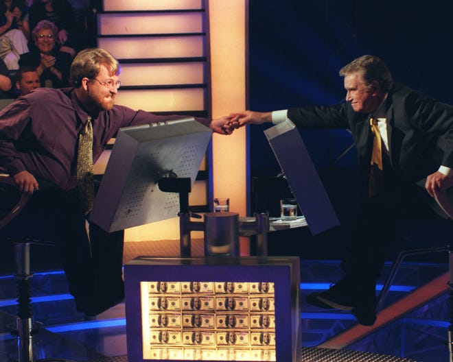 Doug Van Gundy, left, of Marlington, West Virginia, a $250,000 winner on ABC's "Who Wants to Be a Millionaire?," is presented with his quarter-million dollar check by Regis Philbin on Aug. 23, 1999.