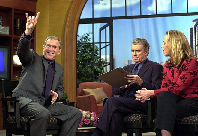Texas Gov. George W. Bush, then the Republican presidential nominee , gives the "Hook 'em horns" sign of Texas while appearing on "Live! With Regis" with host Regis Philbin and guest co-host Susan Hawk of "Survivor" in New York on Sept. 20, 2000.