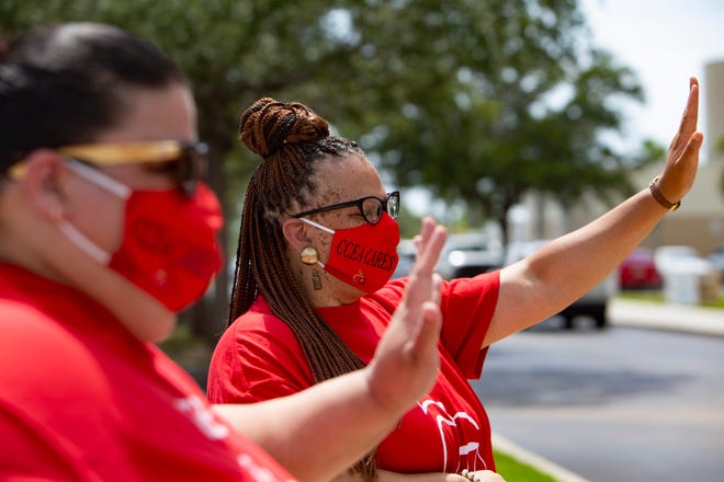 Immokalee High School teacher Raquell Ruppert, left, and Immokalee Middle School teacher Quinetta Ryal wave to demonstrators as they drive past the Collier County Public Schools Dr. Martin Luther King, Jr. Administrative Center offices, Monday, July 27, 2020, in North Naples. Educators, parents and students, drove past the building to voice their concerns reopening schools for the 2020-2021 school year.