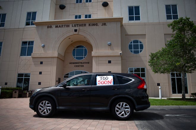 A vehicle drives past the Collier County Public Schools Dr. Martin Luther King, Jr. Administrative Center offices on Monday, July 27, 2020, to demonstrate against reopening schools this fall.