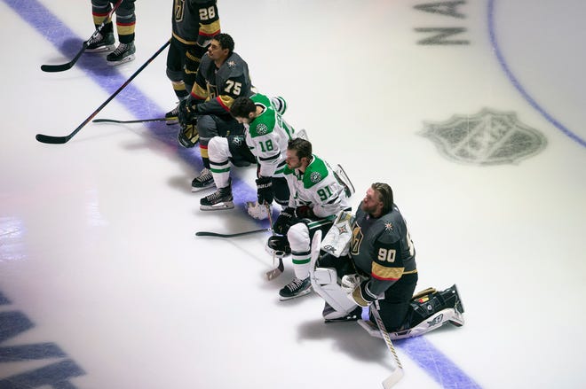 The Dallas Stars' Jason Dickinson (18) and Tyler Seguin (91) and the Vegas Golden Knights' Ryan Reaves (75) and Robin Lehner take a knee during the playing of the national anthem.