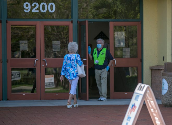 A poll volunteer opens the door for a voter at the Estero Community Center on Tuesday, August 18, 2020.