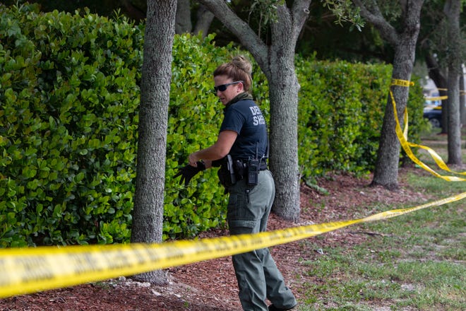 A Collier County Sheriff's Office deputy searches for evidence along Airport-Pulling Road as investigators look in to a homicide at the Home Depot in East Naples on Friday, Aug. 21, 2020,