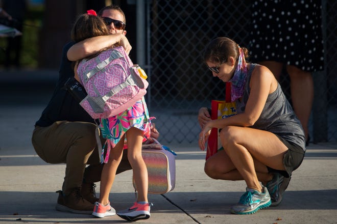 Larry and Lianne Martin hug their daughter Riley Martin as she begins her first day of kindergarten at Lake Park Elementary School in East Naples, Monday, August 31, 2020.