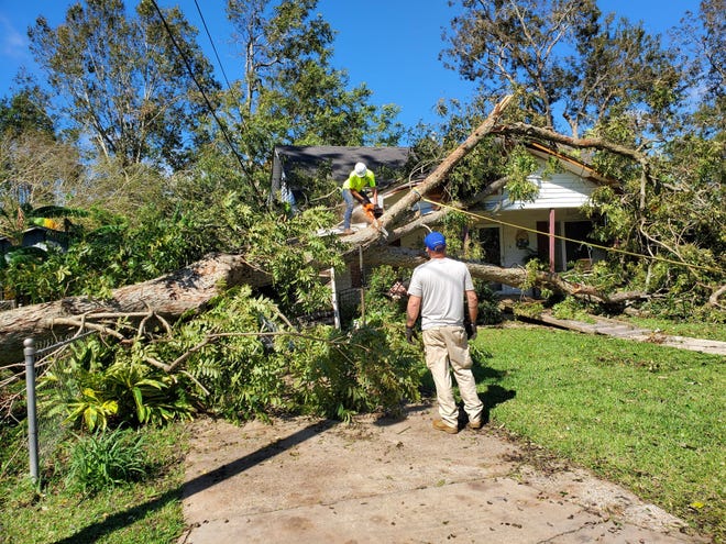 In the aftermath of Hurricane Delta, Marco Patriots and first responders cut a tree that fell on top of the house of an 89-year-old woman in Abbeville, Louisiana on Oct. 10, 2020.