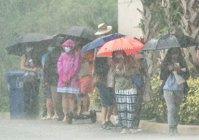 Voters stand in the rain while waiting in line to cast their ballots at the during the first day of early voting at the Palm Gardens Branch Library in Palm Beach Gardens , Florida on October 19, 2020. (GREG LOVETT / THE PALM BEACH POST)