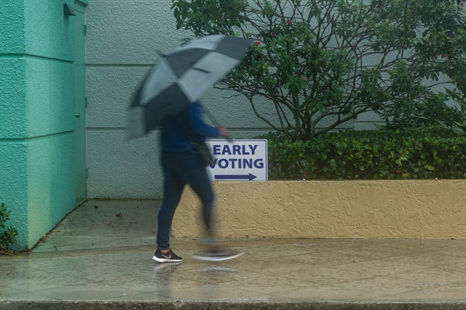 A woman walks under the protection of her umbrella toward the early voting site at the Palm Beach County Library on Summit Blvd., Monday, October 19, 2020. Statewide early voting started today. (JOSEPH FORZANO / THE PALM BEACH POST)