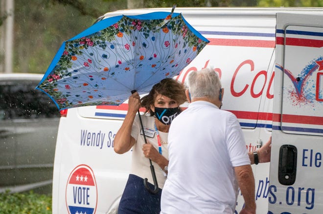 Palm Beach County Supervisor of Elections Wendy Satory Link holds onto her umbrella during a big gust of wind on the first day of early voting in Palm Gardens Branch Library in Palm Beach Gardens , Florida on October 19, 2020. (GREG LOVETT / THE PALM BEACH POST)