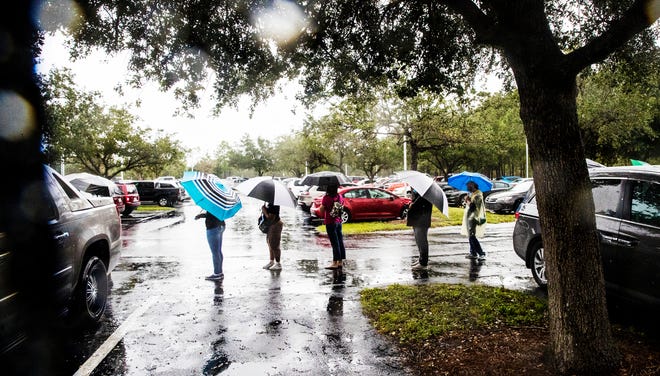 Voters wait in a steady down pour to cast their ballot during early voting at East County Regional Library in Lehigh Acres on Monday, October 19, 2020.