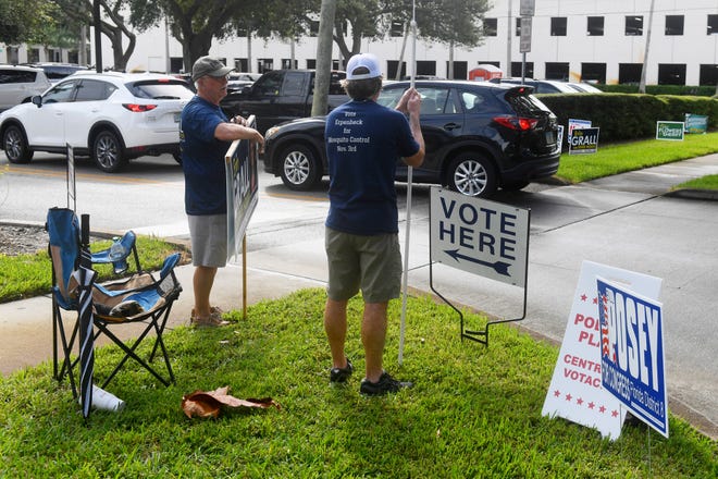 Bernie Grall (left) and Matt Erpenbeck, running for Indian River Mosquito Control District Seat 3, stand at the entrance to the parking lot of the Indian River County Library on the first day of early voting for the general election on Monday, Oct. 19, 2020, in Vero Beach.