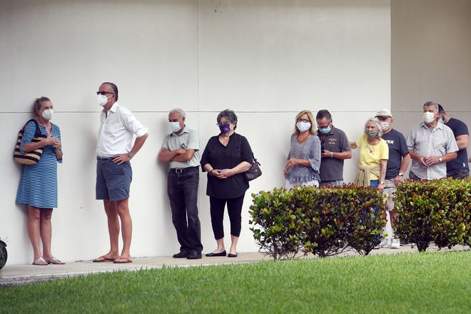 A line begins to form around the outside wall of the Indian River County Library on Monday, Oct. 19, 2020, as community members gather on the first day of early voting in Vero Beach. See more photos .