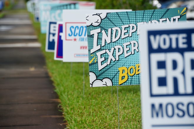 Campaign signs line the sidewalk in front of the Indian River County Library on Monday, Oct. 19, 2020, as voters arrive to vote on the first day of early voting in Vero Beach.