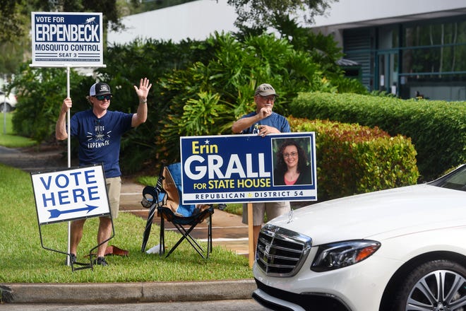 Matt Erpenbeck (left), running for Indian River Mosquito Control District Seat 3, and Bernie Grall stand at the entrance to the parking lot of the Indian River County Library on the first day of early voting for the general election on Monday, Oct. 19, 2020, in Vero Beach.