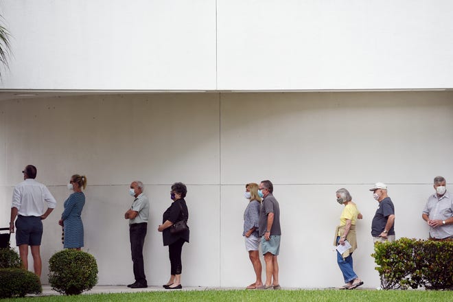 A line forms outside Indian River County Library in Vero Beach, Fla., on Monday, Oct. 19, 2020, the first day of early voting in the county.