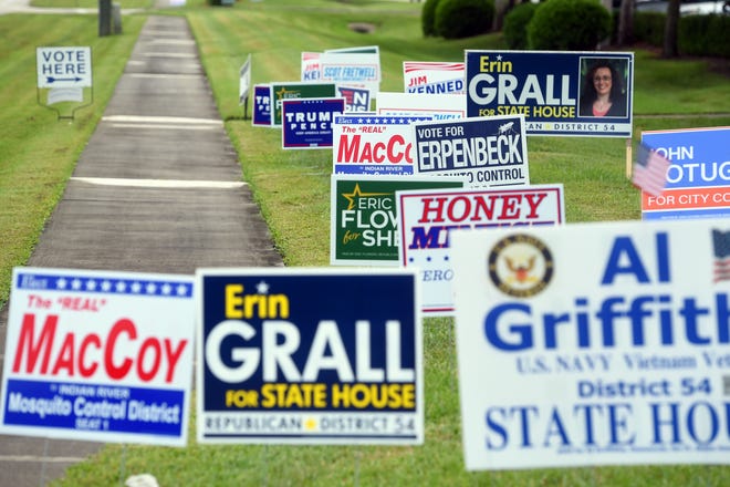 Campaign signs line the sidewalk in front of the Indian River County Supervisor of Elections office on Monday, Oct. 19, 2020, as voters arrive to vote on the first day of early voting in Vero Beach, Fla.