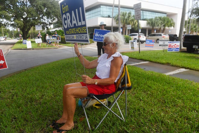 Connie Webb, of Vero Beach, waves to passing motorists near the entrance to the Indian River County Library on the first day of early voting for the general election on Monday, Oct. 19, 2020, in Vero Beach.