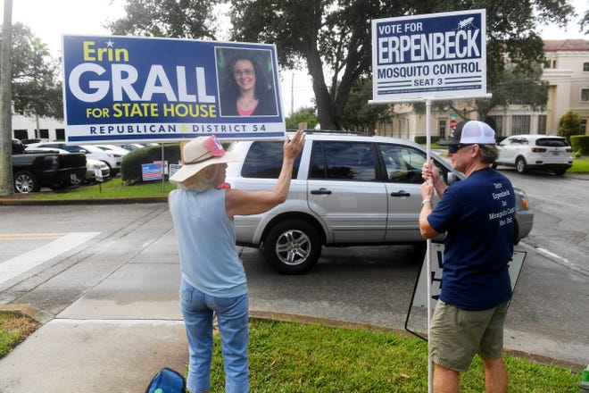 Cathy Anderson (left) and Matt Erpenbeck, running for Indian River County Mosquito Control District Seat 3, hold campaign signs at the entrance to the Indian River County Library on the first day of early voting on Monday, Oct. 19, 2020, in Vero Beach.