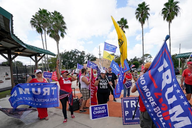 Supporters of President Donald Trump wave flags and shout outside a campaign rally where former President Barack Obama spoke to a crowd that supported Democratic presidential candidate former Vice President Joe Biden Tuesday, Oct. 27, 2020, in Orlando, Fla.