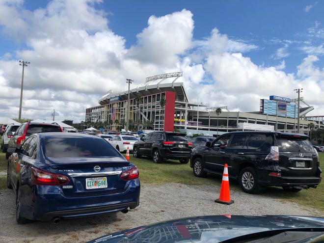 Vehicles line up outside Camping World Stadium in Orlando to hear former President Obama speak at a drive-in rally for Joe Biden Tuesday, Oct. 27, 2020.