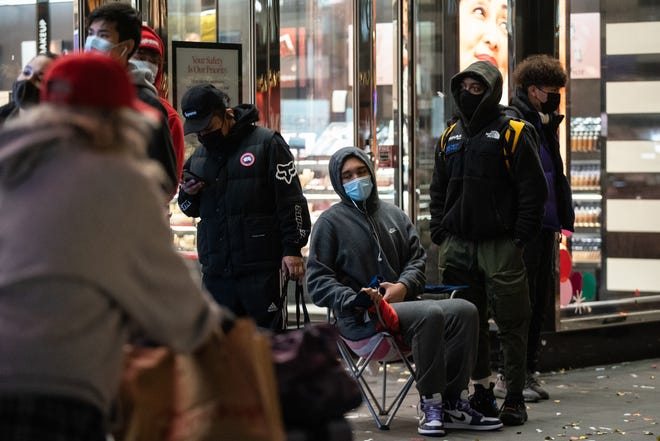 People wearing protective masks wait in line to enter Foot Locker store during Black Friday on November 27, 2020 in New York.