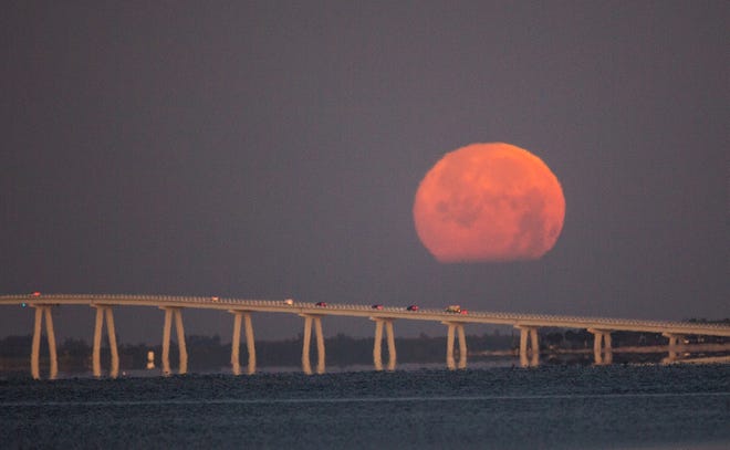 The almost full moon sets over the Sanibel Causway at dawn on Friday, February 26, 2021. The moon will be full on Saturday.
