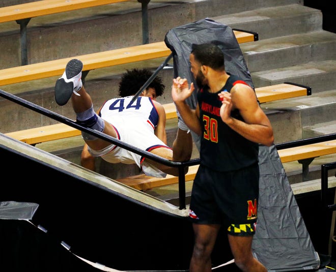 First round: Connecticut guard Andre Jackson crashes into the stands as Maryland forward Galin Smith watches during the game at Mackey Arena.
