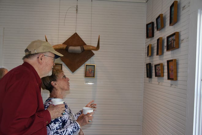 Ron and Jean Bell choose which painting to buy. Marco Island artist Jo-Ann Sanborn is having an exhibit of her cow paintings, titled “Florida on the Hoof,” at Roberts Ranch museum in Immokalee.