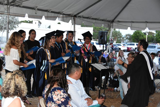 Teacher Chris Dayett leads a choir in "For Good." Marco Island Academy graduated its senior class Friday evening in a commencement ceremony at Veterans' Community Park.