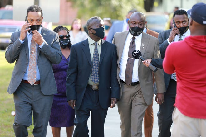 Marcus Arbery, 2nd from left, and his attorney Ben Crump talk with media as they walk toward the Glynn County Courthouse on Monday for the first day of jury selection in the trial for the 3 men accused of killing Ahmaud Arbery.