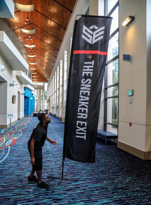 A worker sets up a banner just prior to the start of the Sneaker Exit trade show at the Palm Beach Convention Center Sunday, January 16, 2022.