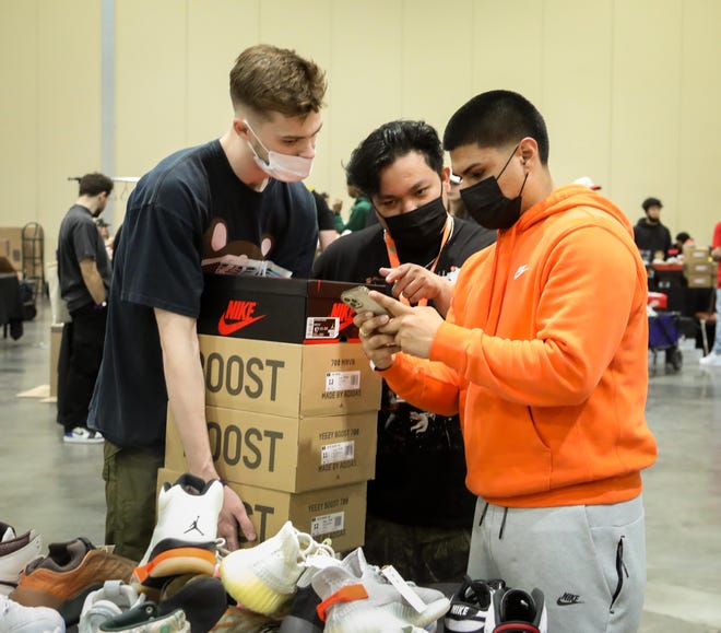 (from left) Alex Tunnell, owner of two sneaker and vintage apparel shops in Alabama, and Alan Overa, his store manager, purchase four pairs of sneakers from Kickswithme owner Pablo, during the Sneaker Exit trade show at the Palm Beach Convention Center Sunday, January 16, 2022.