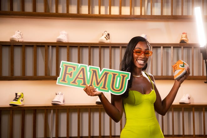 Caitlyn Davis, a Florida A&M University alumna, shows off her FAMU spirit for a photo while holding a sneaker that she designed. David teamed up with Nike to create a FAMU inspired shoe. The shoe was released as part of the "HBCU Dunk Lows" collection.