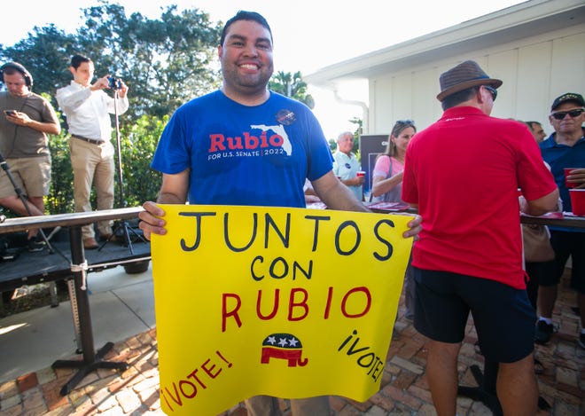 Steve Avila, Royal Palm Beach, poses for a picture while holding a sign that reads in Spanish "Together with Rubio" during an event for Senator Marco Rubio's re-election campaign held at the Sims House on Thursday, October 27, 2022, in Jupiter, FL.