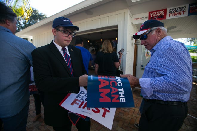 Nicolas Giacalone, a Palm Beach County administrative liason with the Marco Rubio campaign, hands a sign to Larry Dyer, North Palm Beach, during an event for Marco Rubio's re-election campaign held at the Sims House on Thursday, October 27, 2022, in Jupiter, FL.